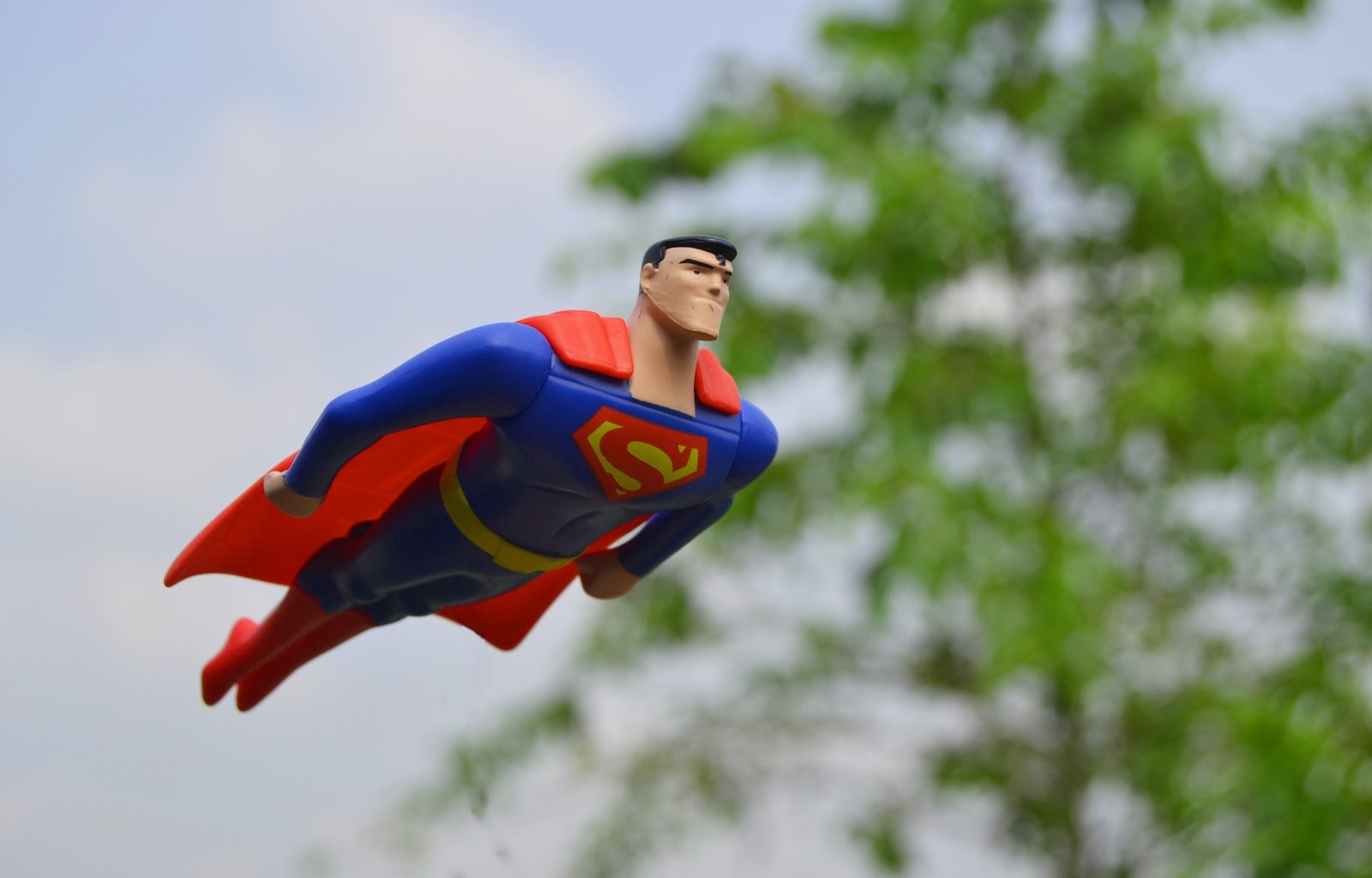 Superman flying near green grass