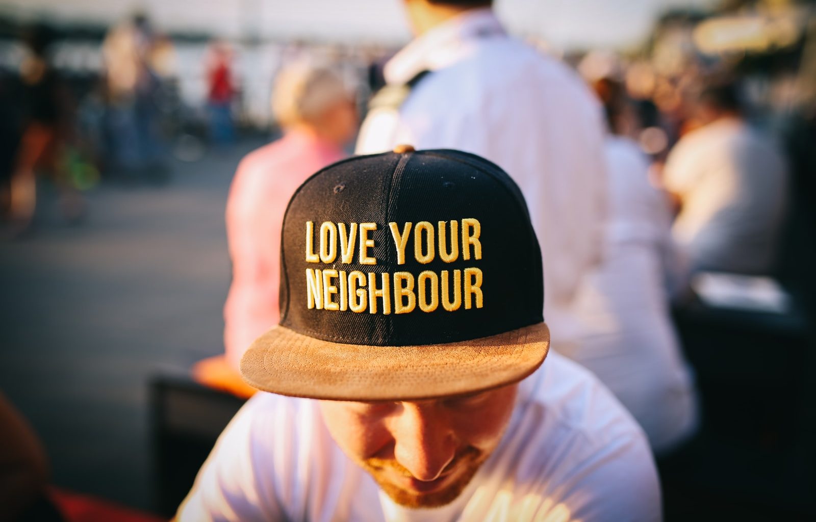 man wearing black cap with love your neighbour print during daytime