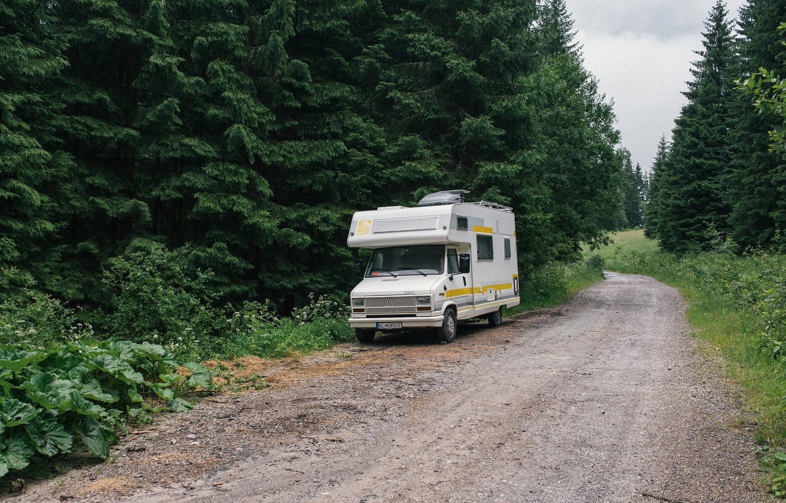 white and green rv on dirt road
