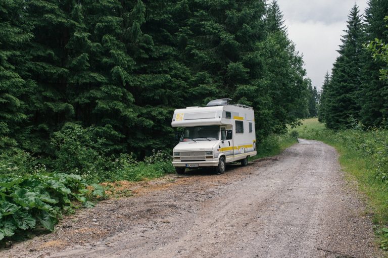 white and green rv on dirt road