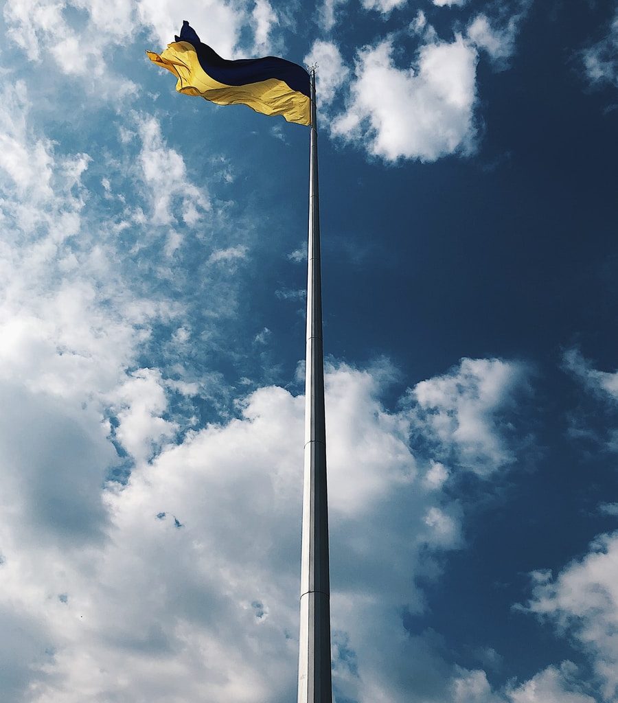 yellow flag under white clouds and blue sky during daytime