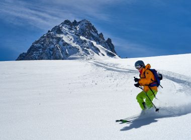 man in orange jacket and black pants riding ski blades on snow covered mountain during daytime