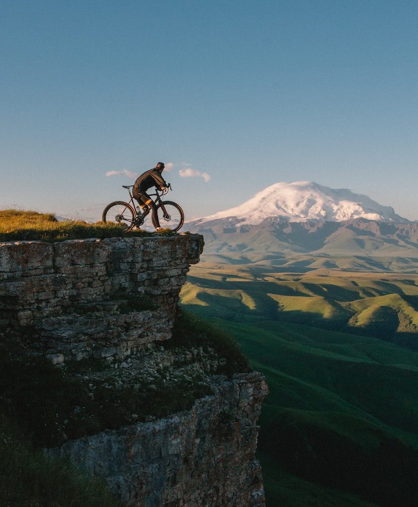 man riding bike on cliff at daytime