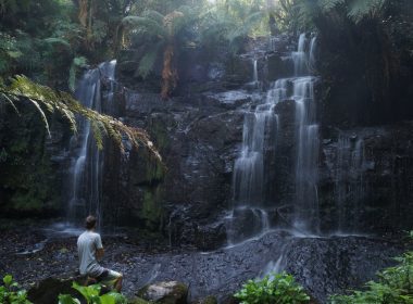 man sitting beside waterfalls