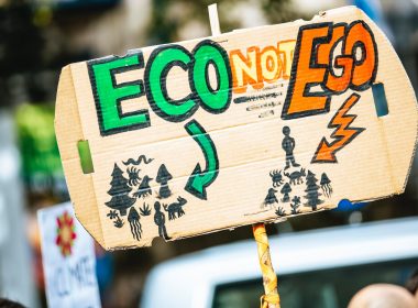person holding Eco Not Ego signage