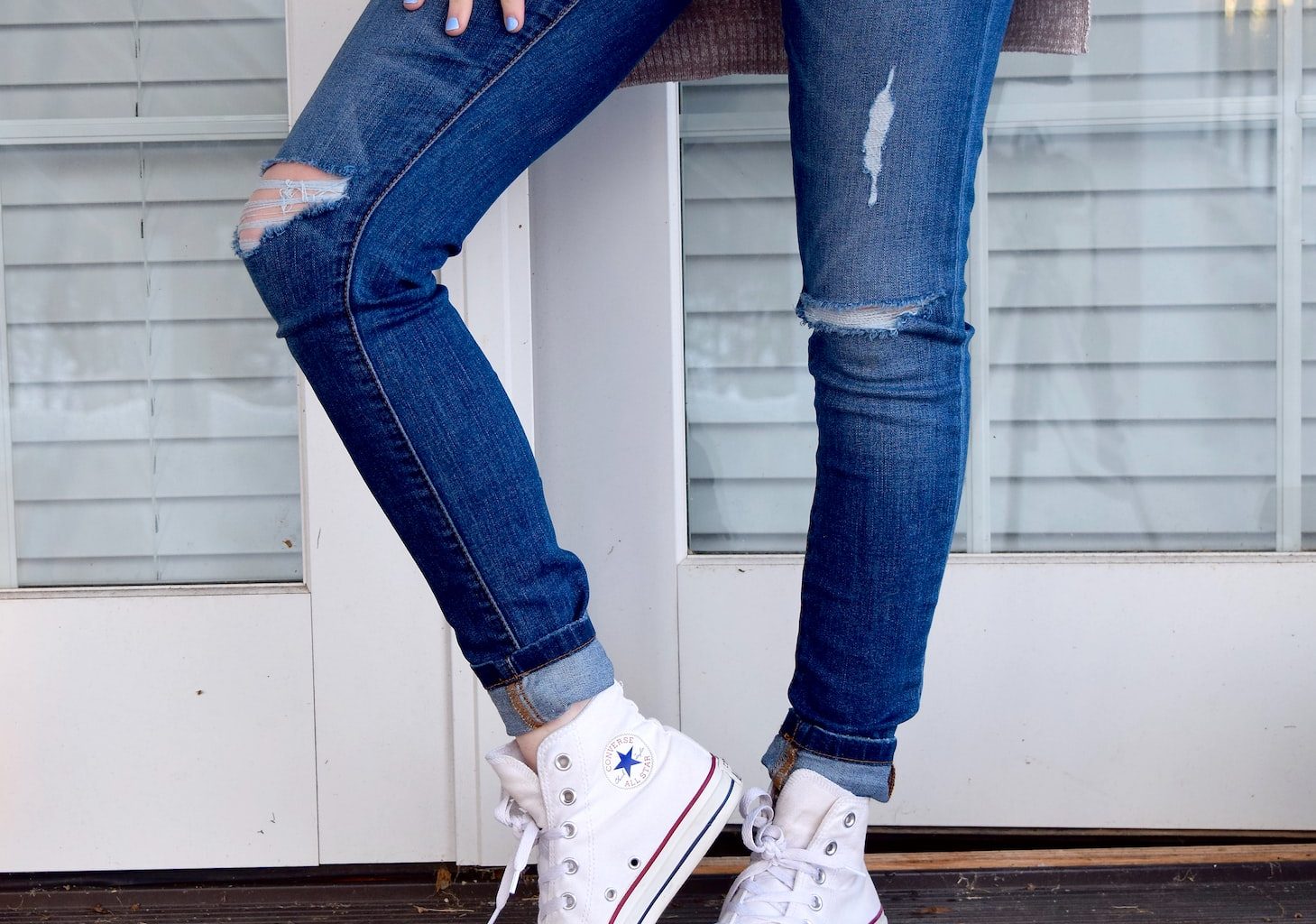 women's distressed blue denim jeans and pair of white Converse Allstar high-tops