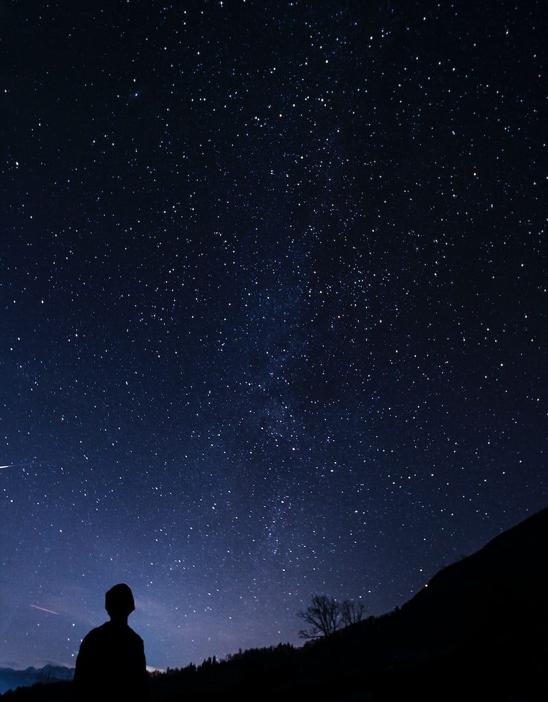silhouette of man looking at milky way
