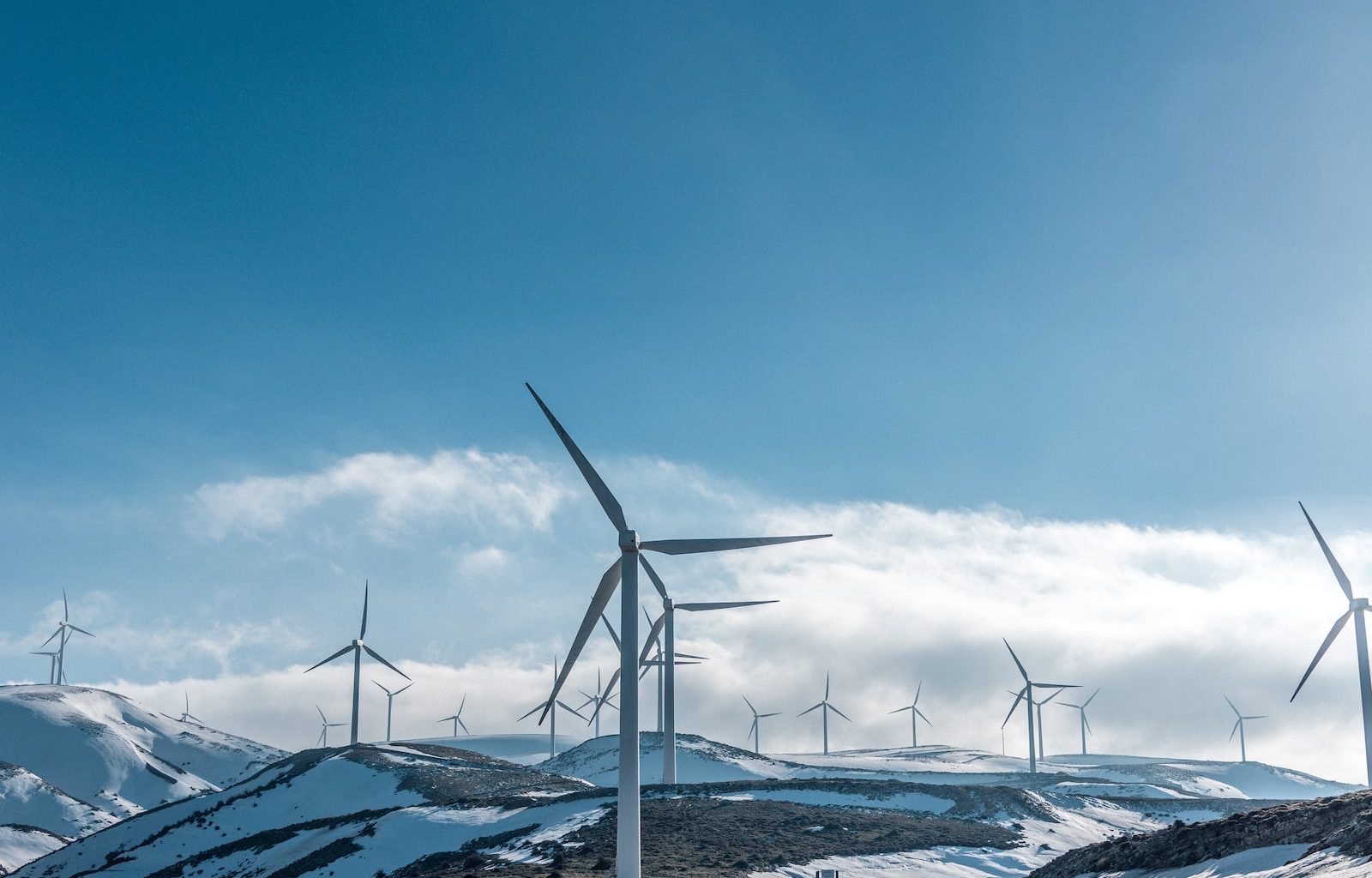 wind turbines on snowy mountain under clear blue sky during daytime