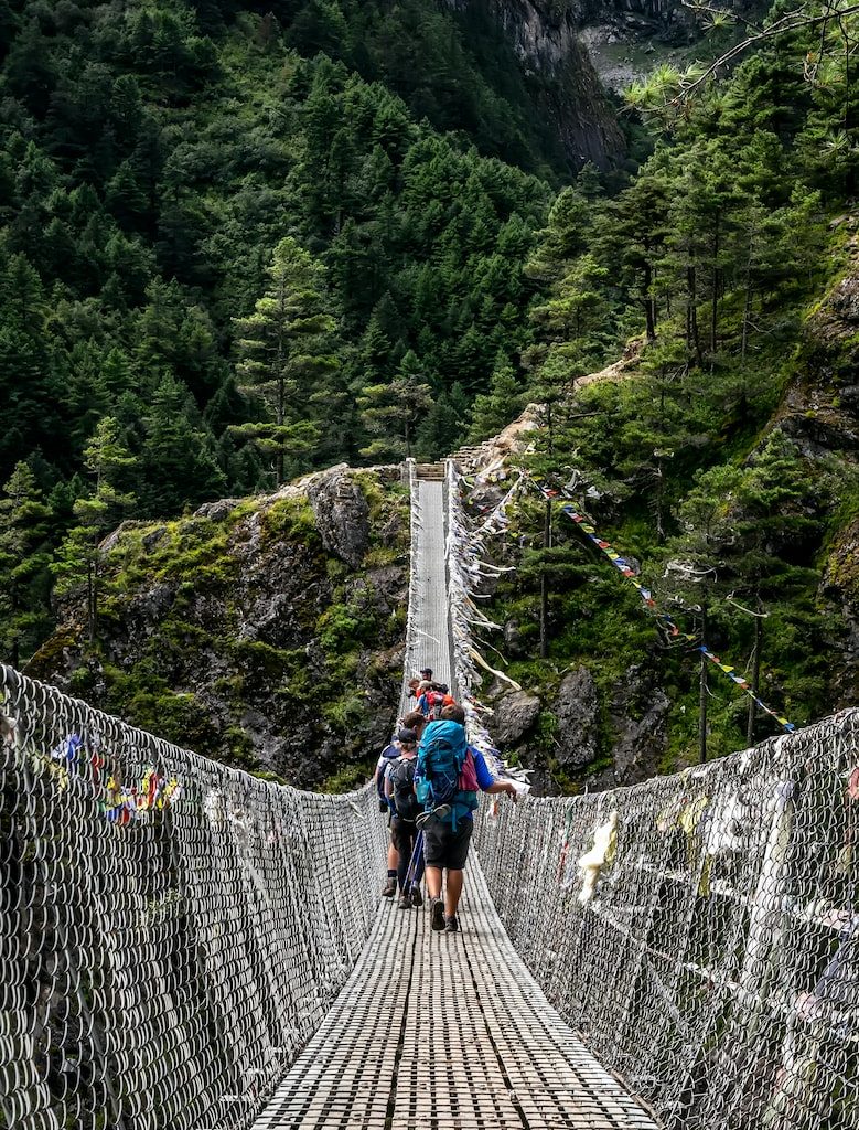 people walking on grey rope bridge during daytime