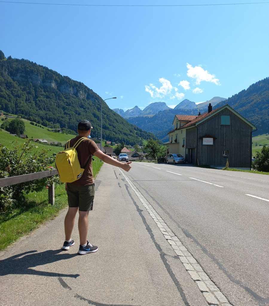 a man with a yellow backpack standing on the side of a road